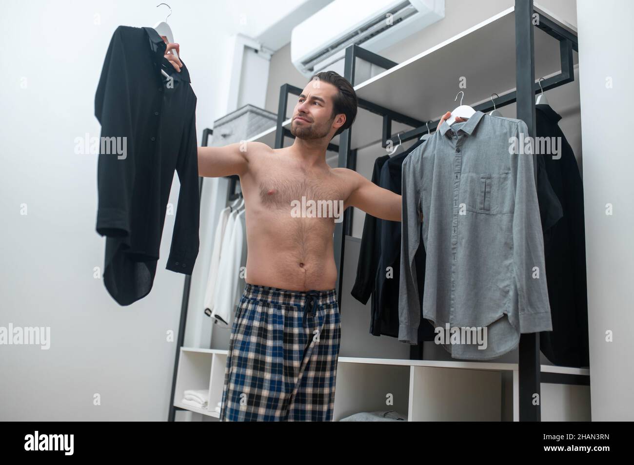 Uomo in pantaloni casa plaid scegliere una camicia da indossare Foto stock  - Alamy