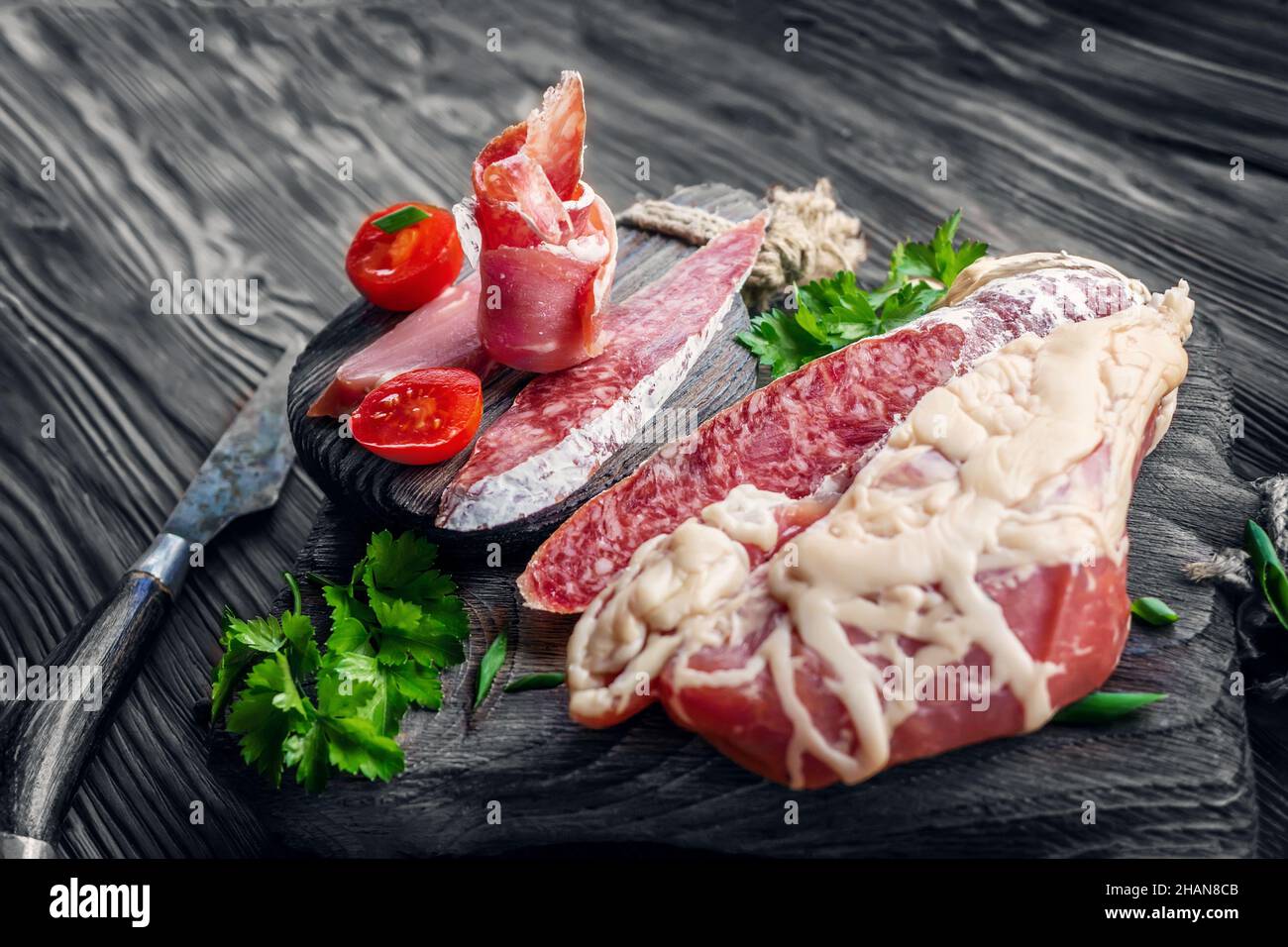 grande pezzo di carne secca in una sottile maglia di grasso interno. Un pezzo di carne fresca affumicata giace sulle foglie di spinaci. Filetto di carne di cervo naturale con Foto Stock