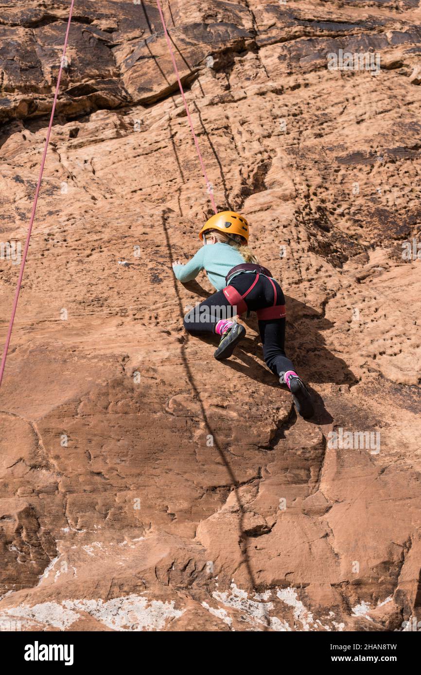 Una bambina di sette anni imparando a scalare la roccia nella zona di arrampicata di Wall Street vicino a Moab, Utah. Foto Stock