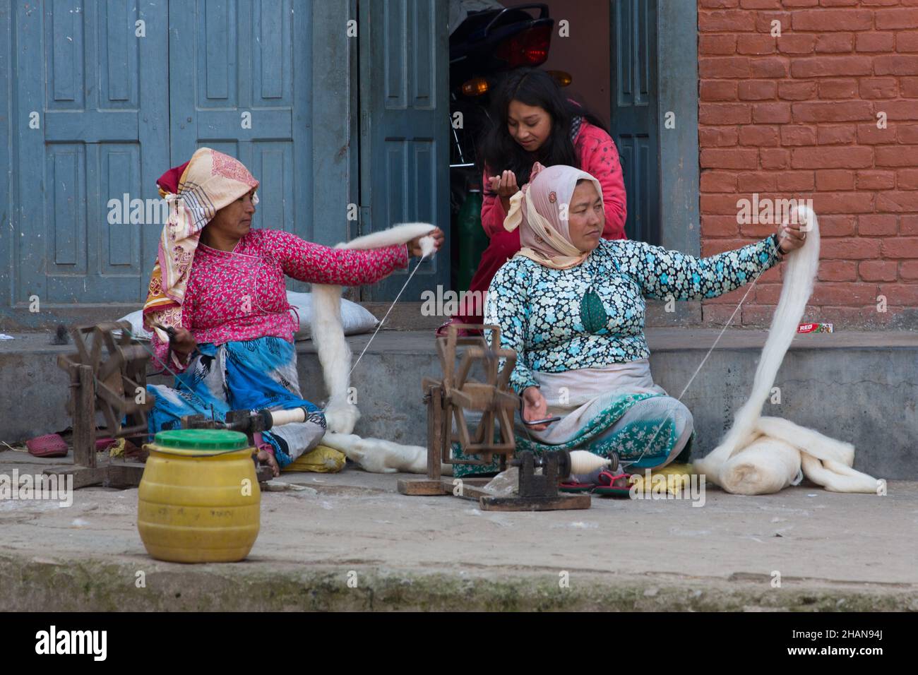 Donne nepalesi filano filo di lana a mano nel borgo medievale di Newari di Khokana. Valle di Kathmandu del Nepal. Foto Stock