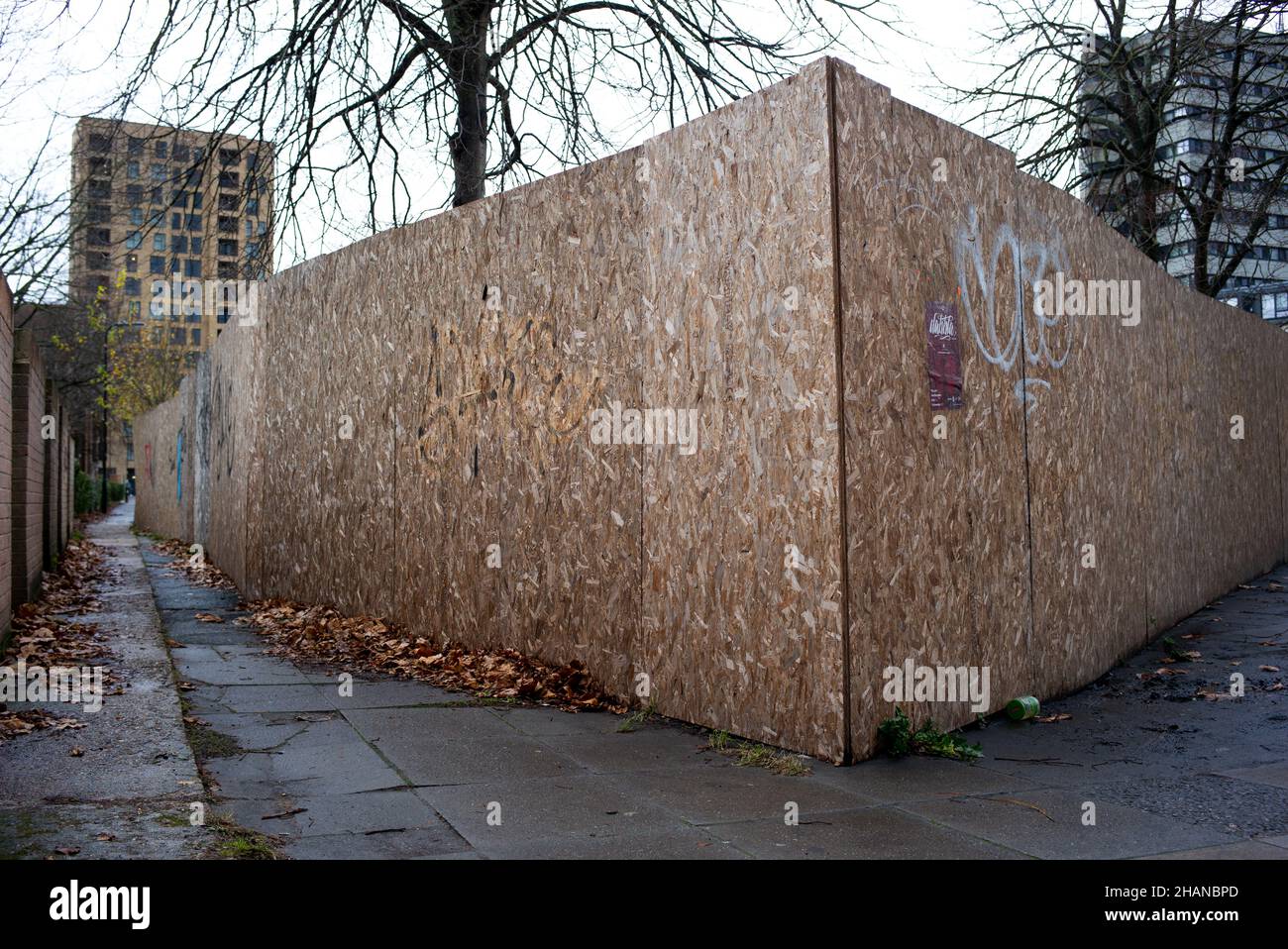 Un vicolo cittadino con una parete laterale in mattoni l'altra scacchiera da un cantiere che crea una scena inquietante che potrebbe essere utilizzata in modo concettuale. Foto Stock