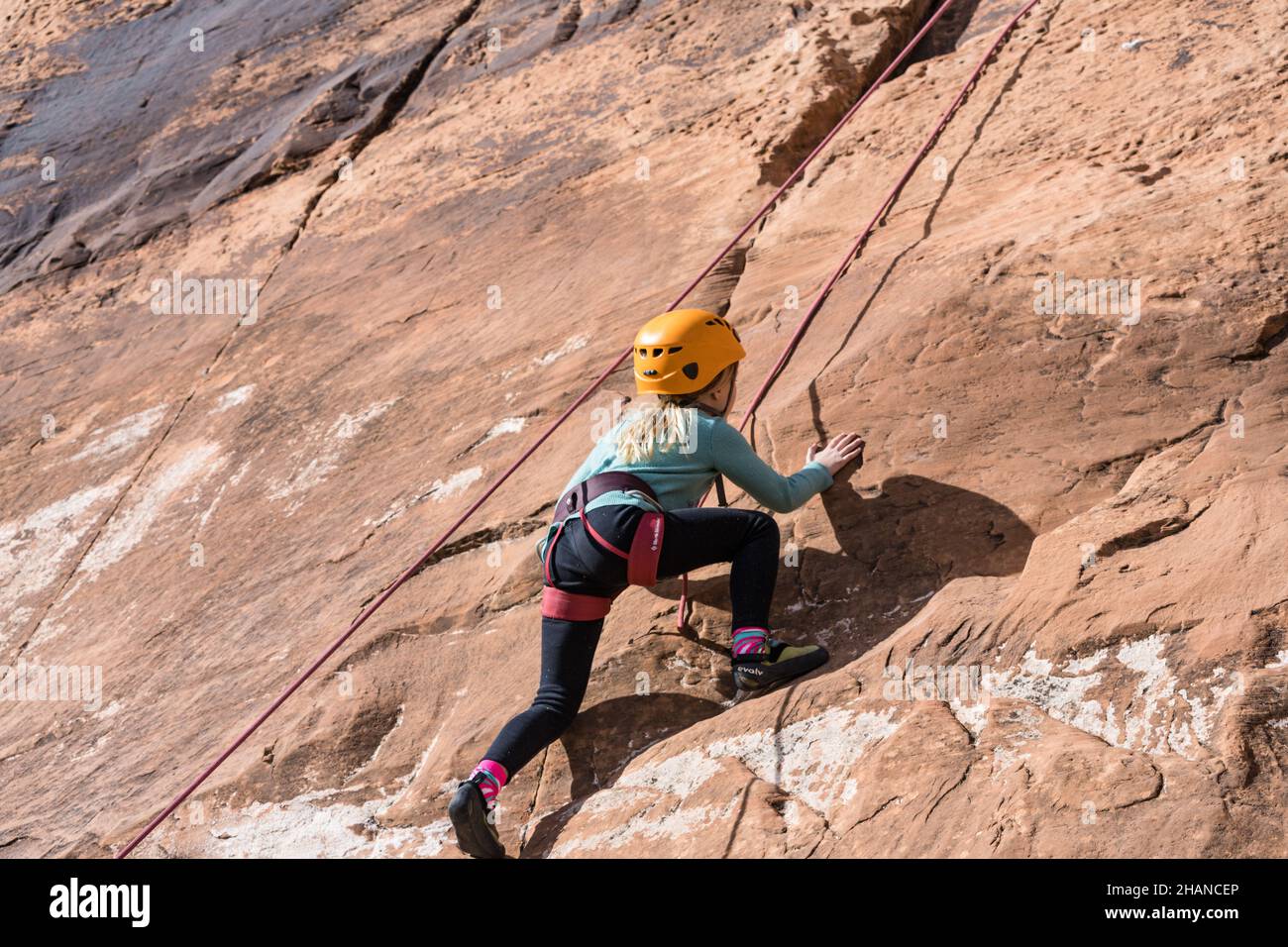 Una bambina di sette anni imparando a scalare la roccia nella zona di arrampicata di Wall Street vicino a Moab, Utah. Foto Stock