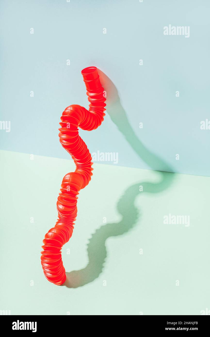 Il tubo pop curvo è appoggiato contro la parete. Vita morta moderna con giocattolo antistress. Foto Stock