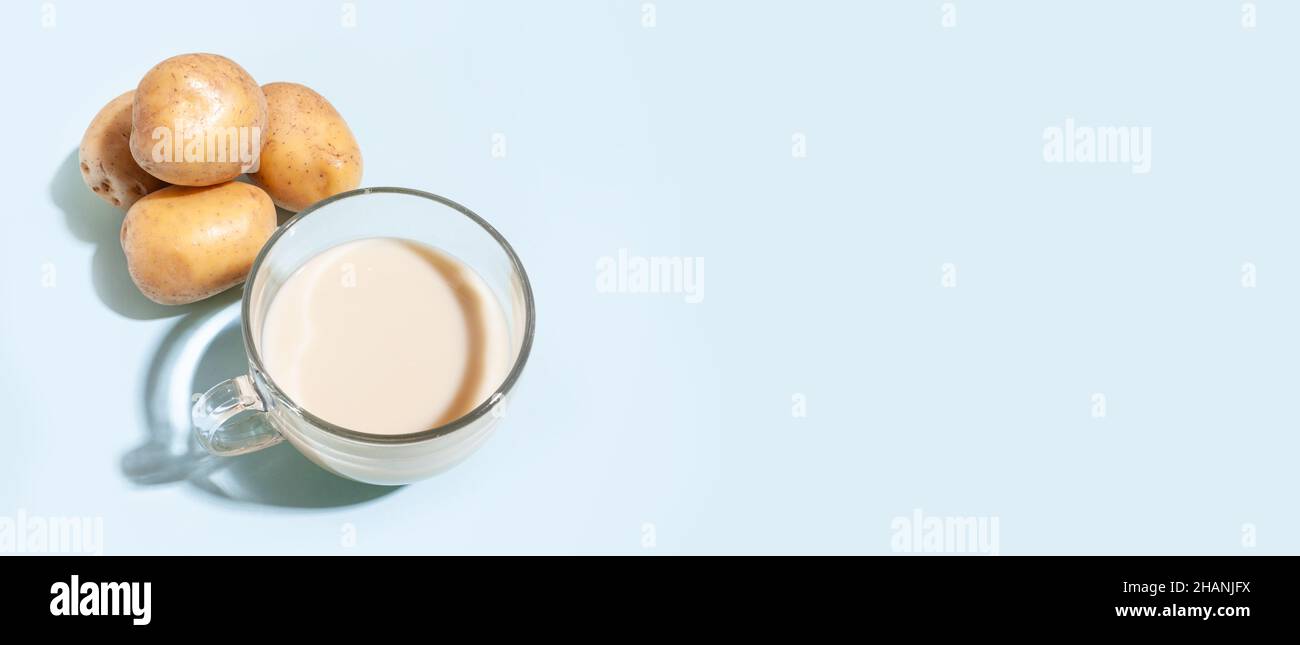 Latte di patate, una tazza con latte e tuberi di patate in formato banner. Latte vegetale alternativo. Foto Stock
