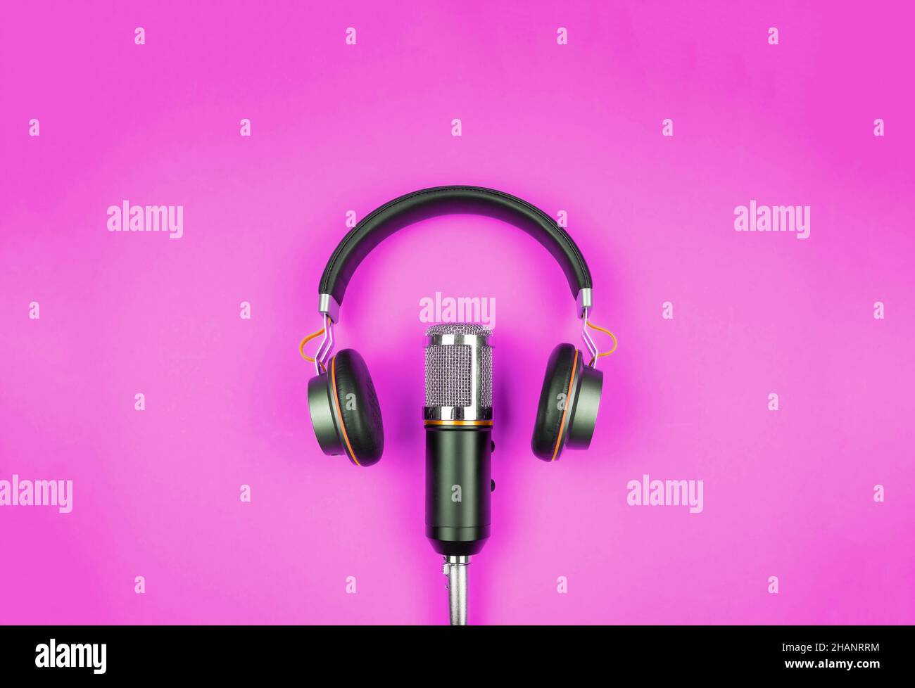 concetto di podcasting, vista direttamente sopra le cuffie e microfono di registrazione su sfondo rosa con spazio copia Foto Stock