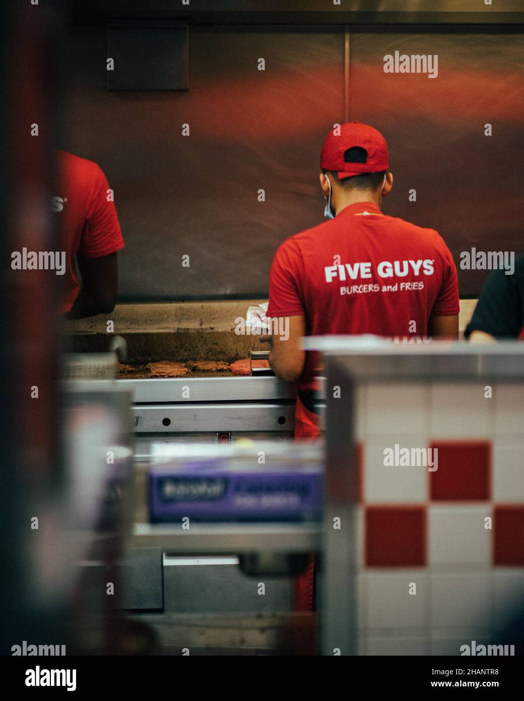 PARIGI, FRANCIA - 23 giugno 2021: Un lavoratore di cinque Guys che fa un hamburger in cucina Foto Stock