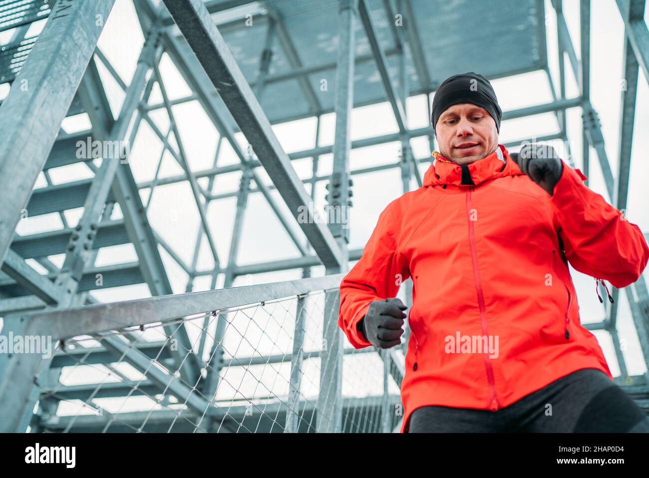 Ritratto in vita di uomo sorridente runner vestito rosso brillante  softshell abbigliamento sportivo e guanti che corrono giù da enormi scale  industriali in acciaio in vino freddo Foto stock - Alamy