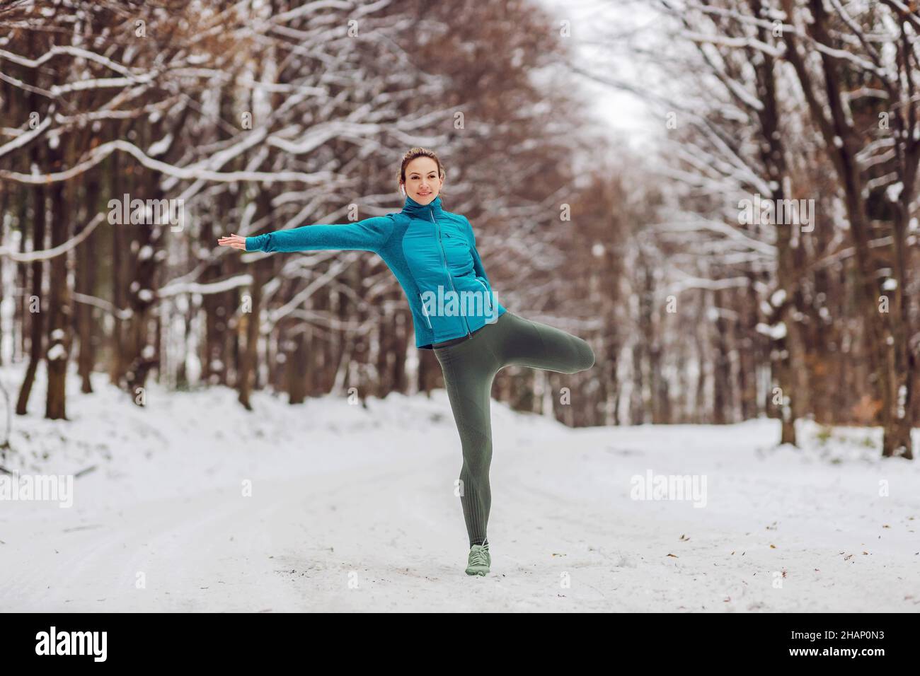 Adatta il bilanciamento sportivo su un piede mentre ti trovi in natura durante la giornata invernale nevosa. Fitness invernale, equilibrio, natura Foto Stock