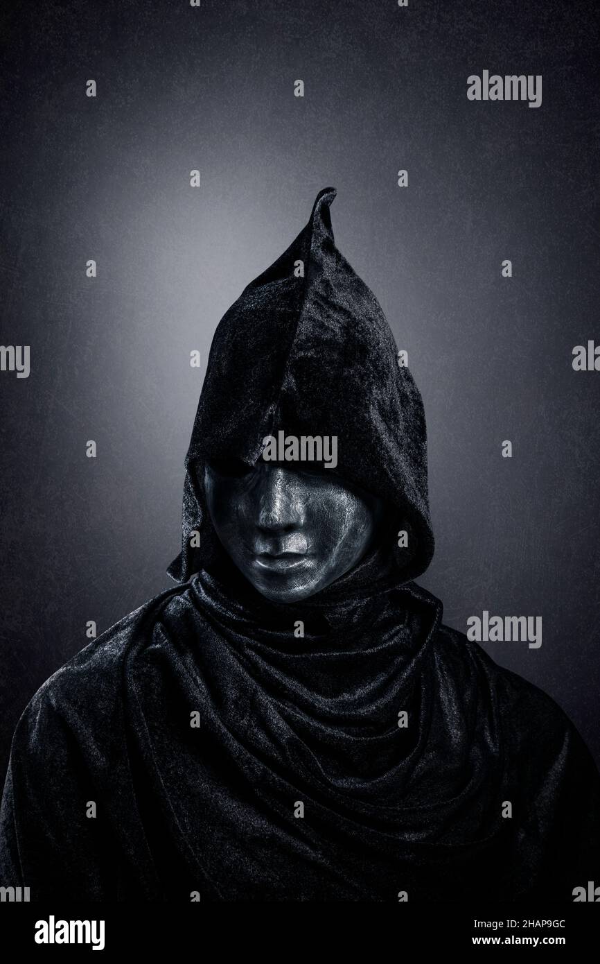 Figura spaventosa con mantello agganciato al buio Foto Stock