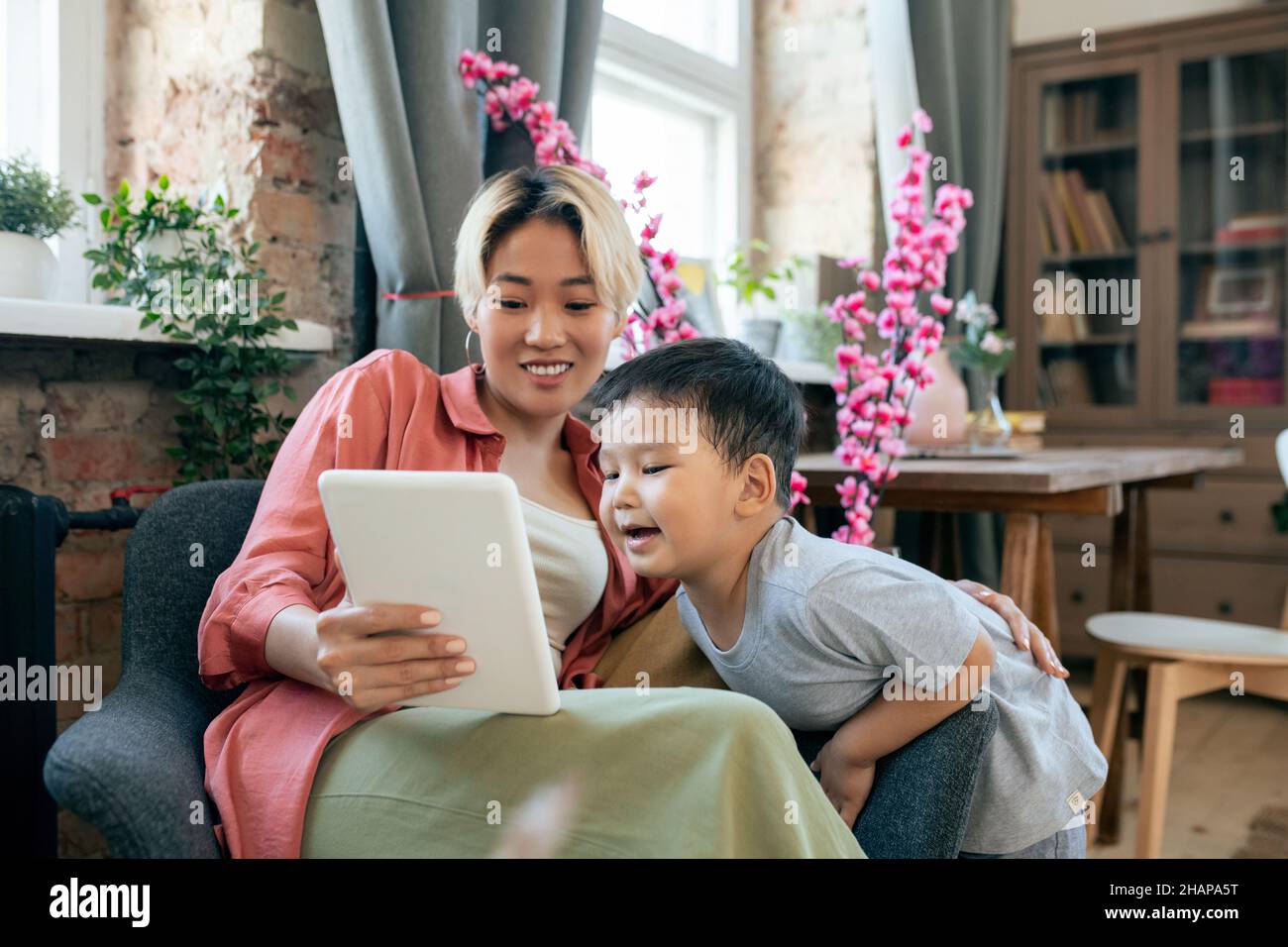Felice madre giovane con il tablet e suo figlio piccolo carino guardando video online in ambiente domestico Foto Stock