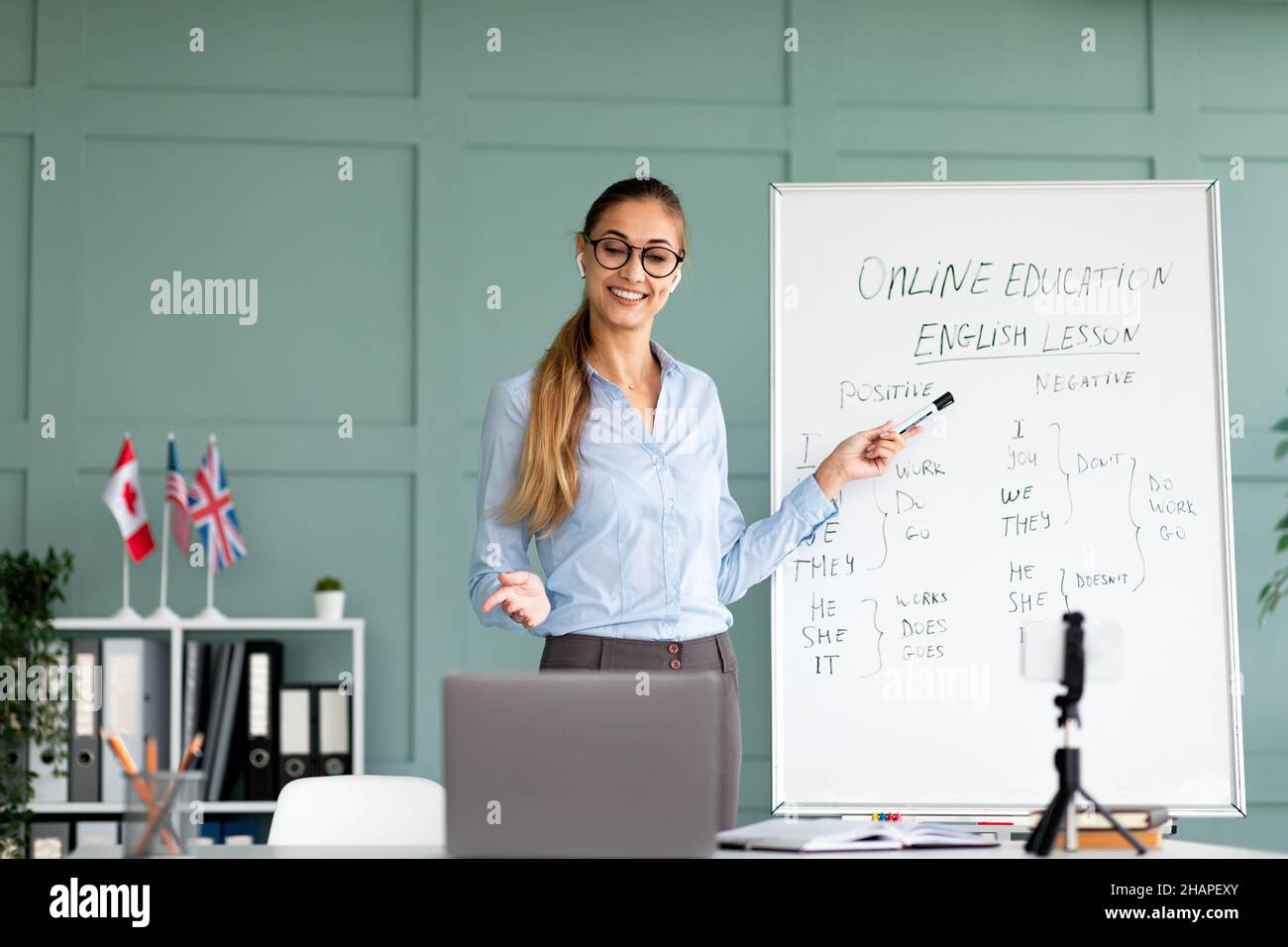 Happy femmina tutor insegnamento regole grammatica inglese per gli studenti on-line, sorridendo a laptop webcamera, spazio libero Foto Stock