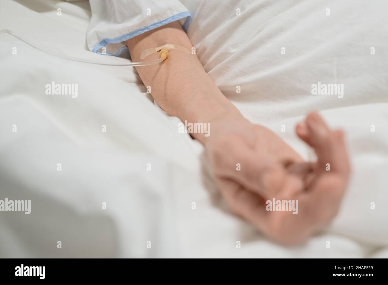 Primo piano della donna anziana che si trova a letto con gocciolamento nel braccio, è sotto l'anestesia Foto Stock