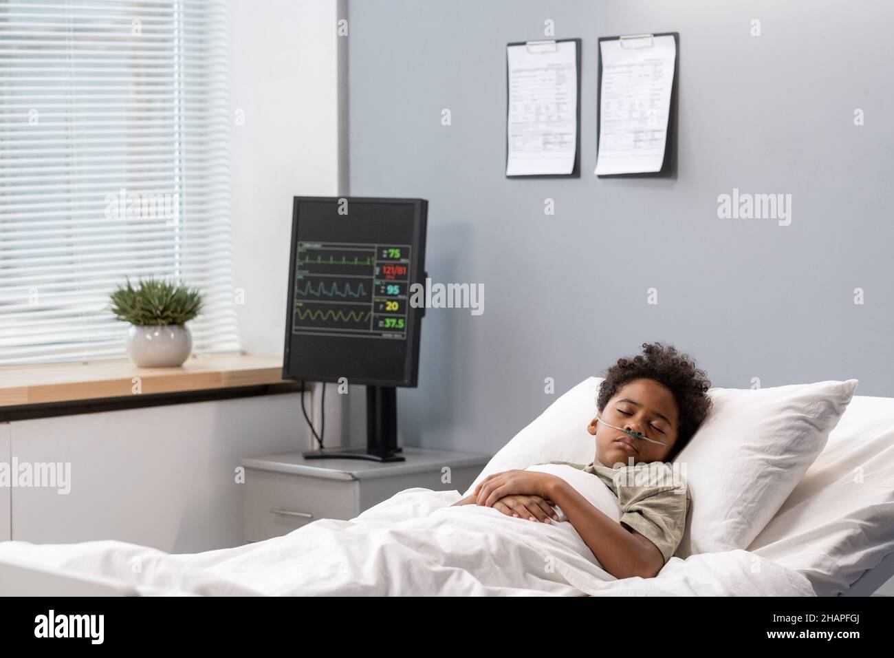 Ragazzino malato che dormiva a letto nel reparto ospedaliero durante la malattia Foto Stock