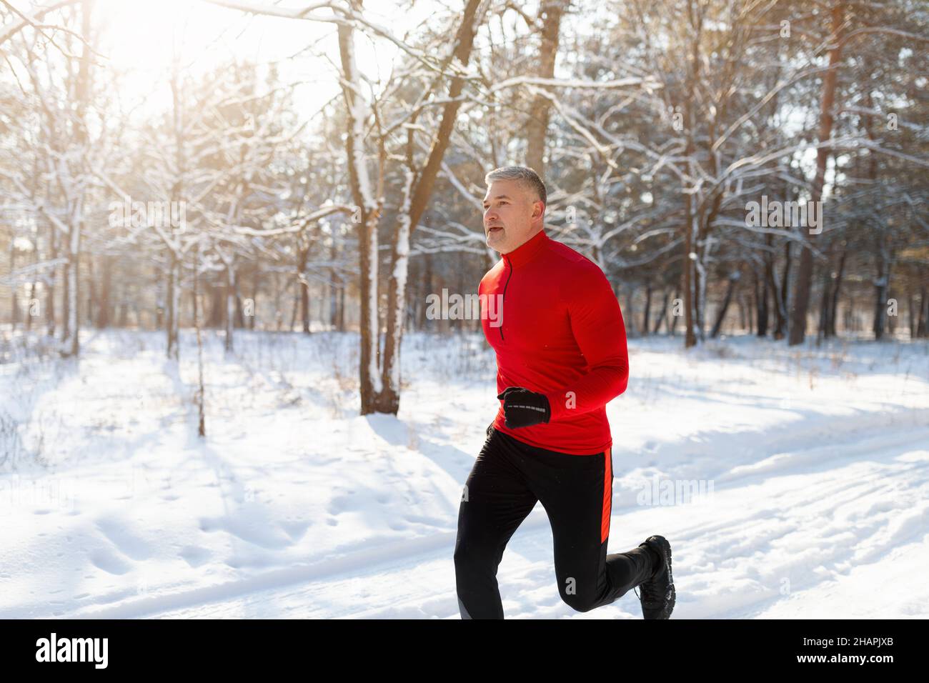 Atletico uomo anziano in abbigliamento sportivo che corre al parco invernale,  jogging all'aperto al mattino soleggiato e gelido, spazio per le copie Foto  stock - Alamy