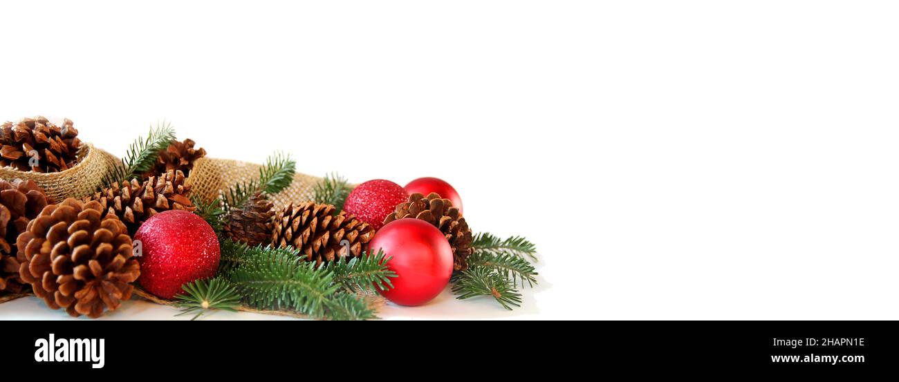 Ornamenti rossi dell'albero di Natale, coni del pino, rami sempreverdi e tessuto di burlap stanno generando una cornice, isolata su uno sfondo bianco bianco bianco bianco bianco bianco bianco bianco bianco bianco bianco. Foto Stock