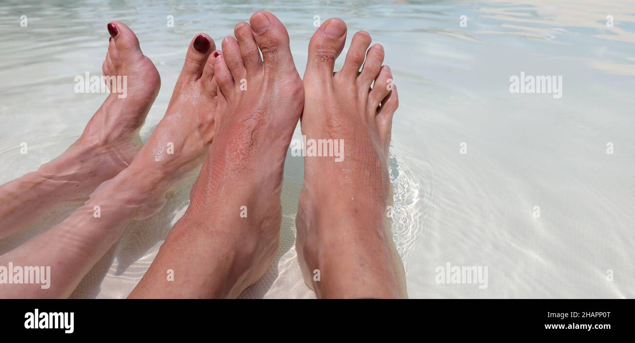 piedi di donna con polacco su unghie e compagno di sesso maschile in piscina durante la luna di miele in resort Foto Stock