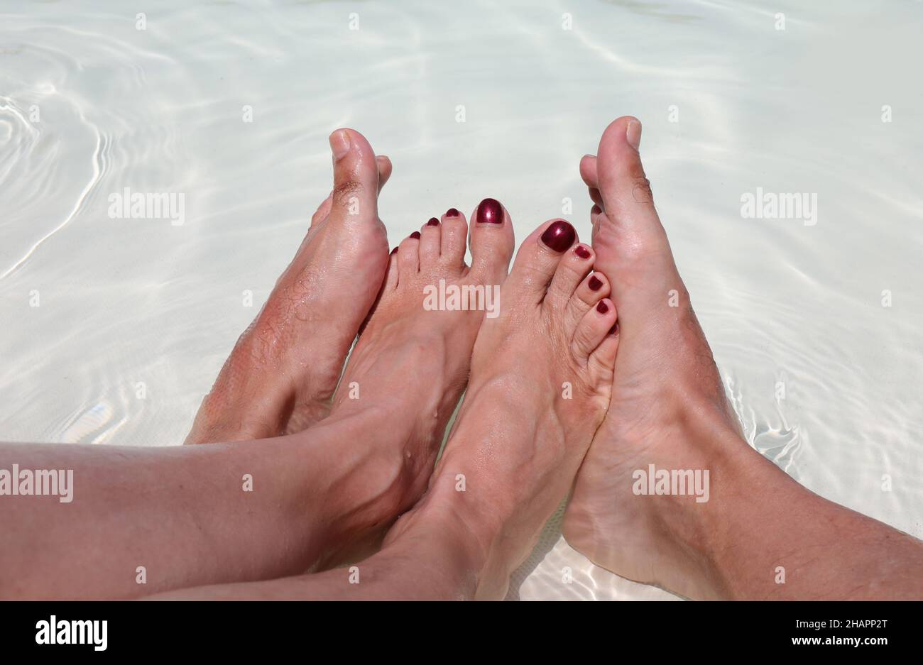 due piedi di sesso maschile circa piedi di giovane moglie in piscina durante la rilassante luna di miele Foto Stock