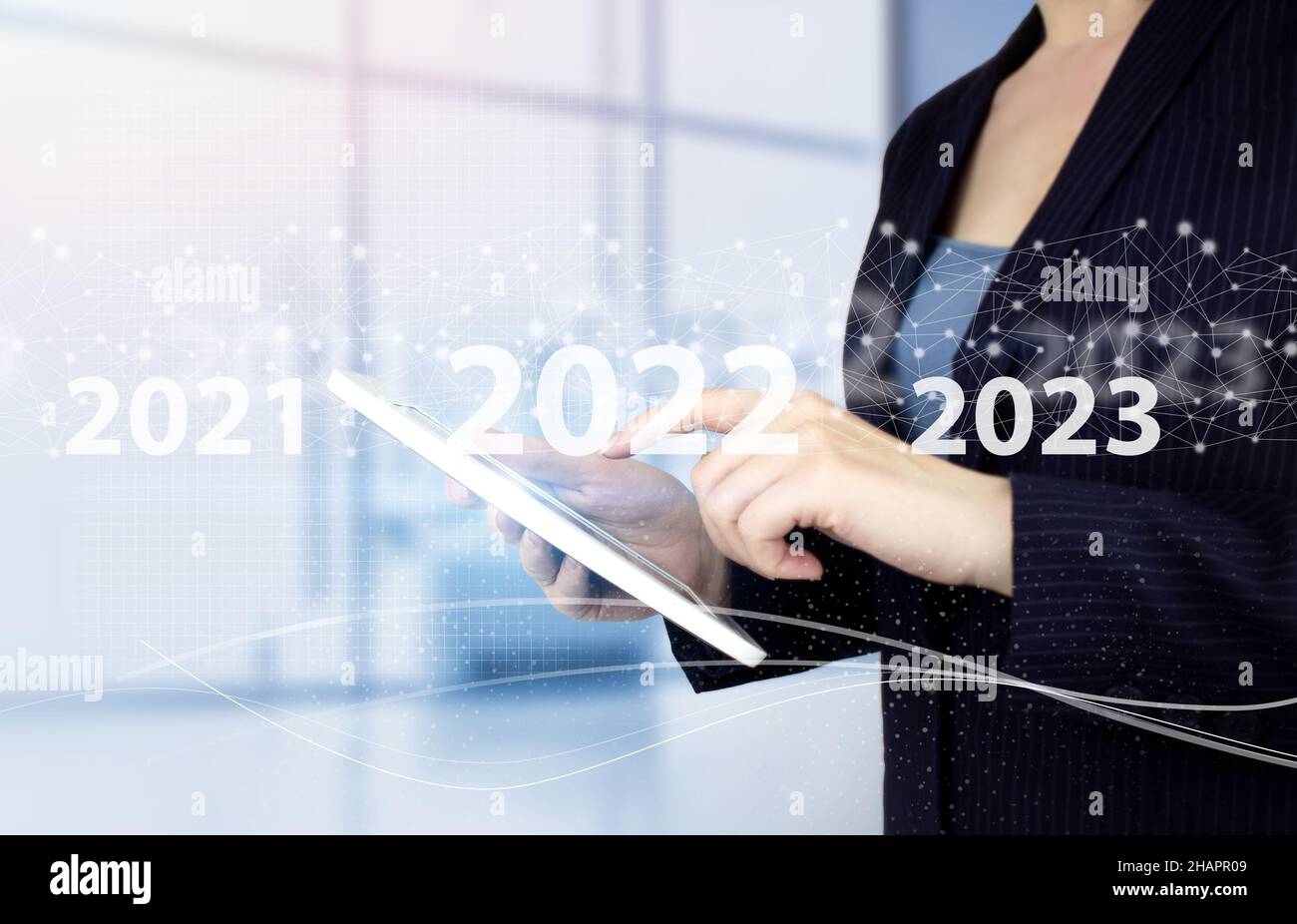 anno nuovo 2022. Toccare a mano il tablet bianco con il segno ologramma digitale 2022 su sfondo sfocato chiaro. Concept inizio nuovo anno 2022 Foto Stock