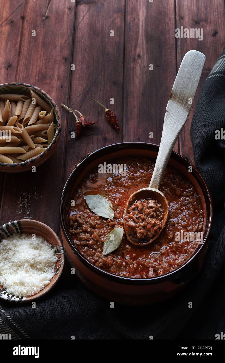 Bolognese fatto in casa o salsa di ragù servita in un recipiente rustico, su legno scuro. Direttamente sopra. Foto Stock