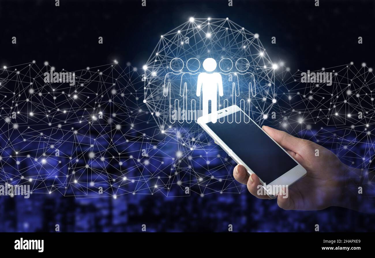 Risorse umane e concetto di team management. Smartphone bianco portatile con ologramma digitale umano, segno leader sulla città scuro sfondo sfocato. COM Foto Stock