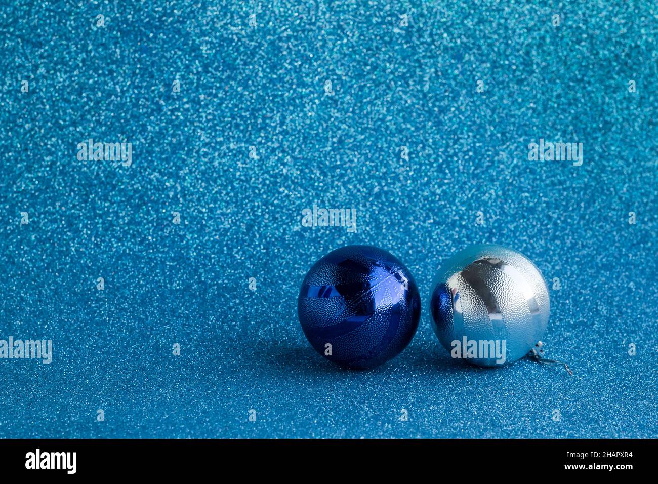Due palle di natale lucenti su superficie blu argentea con spazio per la copia Foto Stock
