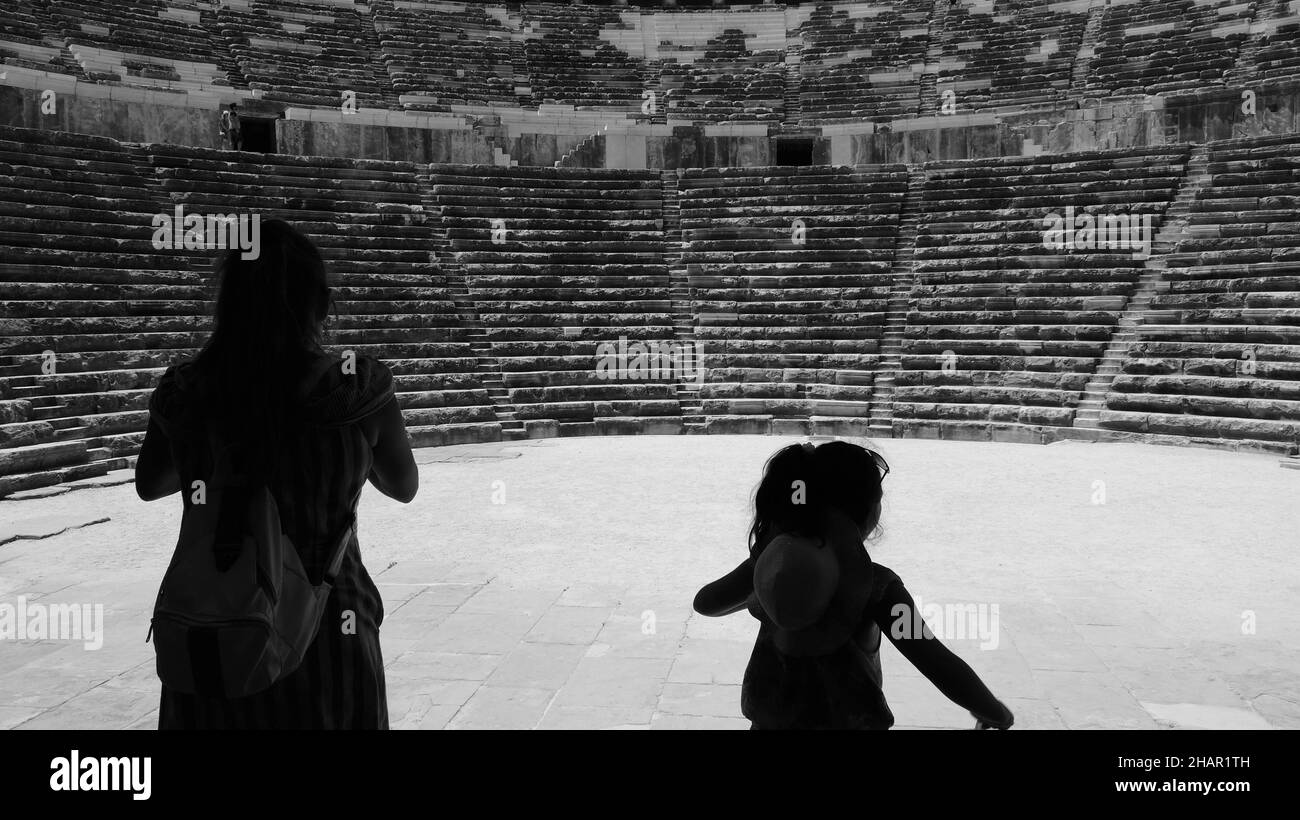 Dietro una madre e sua figlia in silhouette stanno guardando l'antico teatro in Aspendos di Antalya città, Turchia Foto Stock