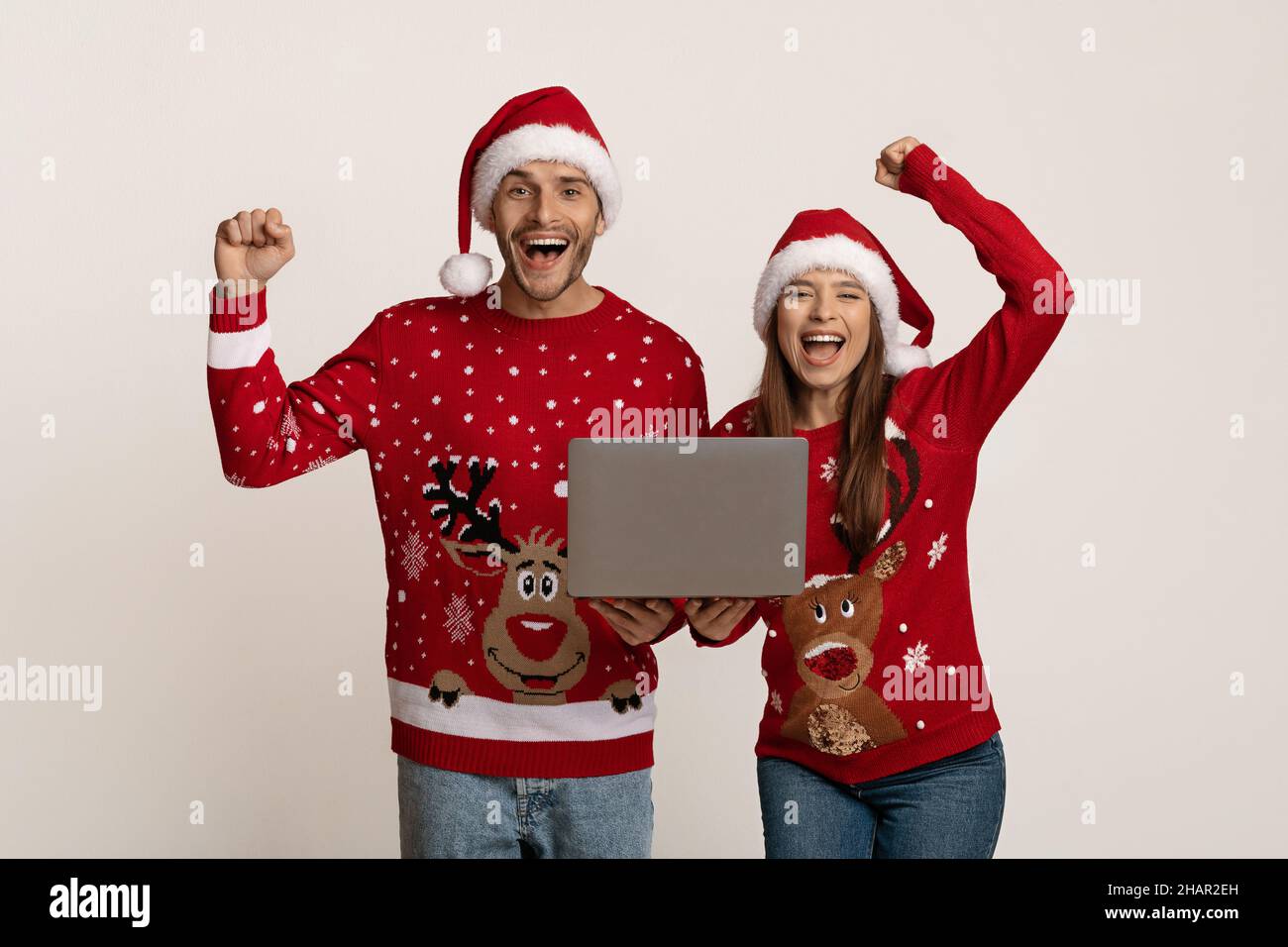 Ritratto di coppia giovane e gioiosa in Babbo Natale cappelli celebrare il successo con notebook Foto Stock