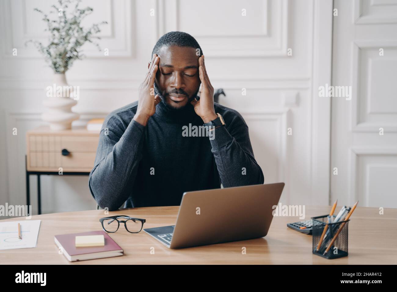 Preoccupato giovane dipendente africano americano che soffre di mal di testa sul posto di lavoro Foto Stock