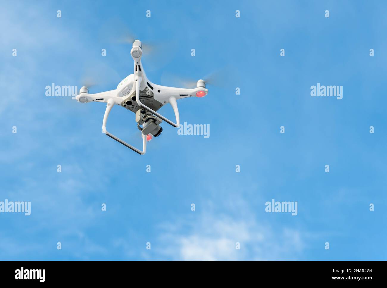 Drone bianco che vola in un cielo blu nuvoloso. Foto Stock