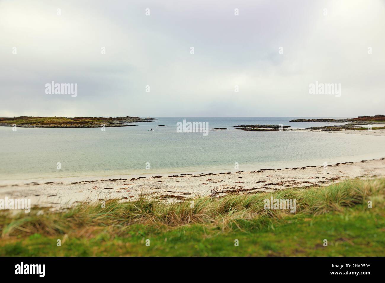 Un solo canoista esplora le acque ancora isolane orlate da sabbia bianca alle spiagge di Traigh sulla strada B8008 vicino a Morar, nella Scozia occidentale Foto Stock