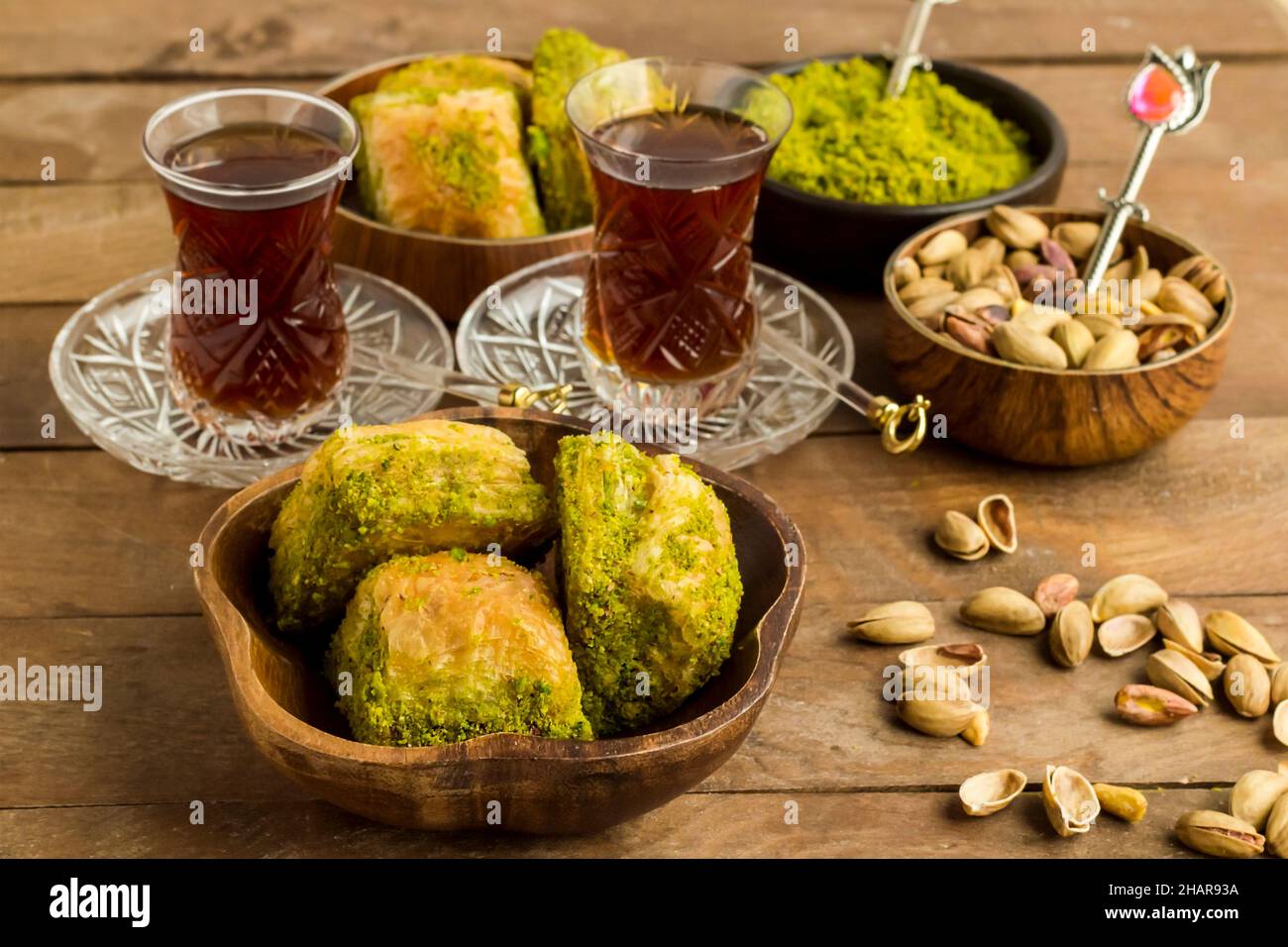 Tradizionale pasticceria turca Dessert Baklava in ciotole di bambù su tavola di legno con tè e pistacchio noci. Foto Stock