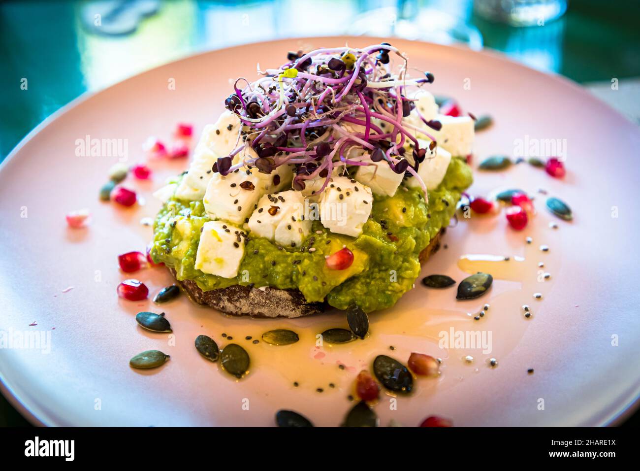Un toast all'avocado con cubetti di feta, semi di zucca, semi di melograno e germogli è servito in un bistrot a Narbonne, dipartimento dell'Aude, Francia. Foto Stock