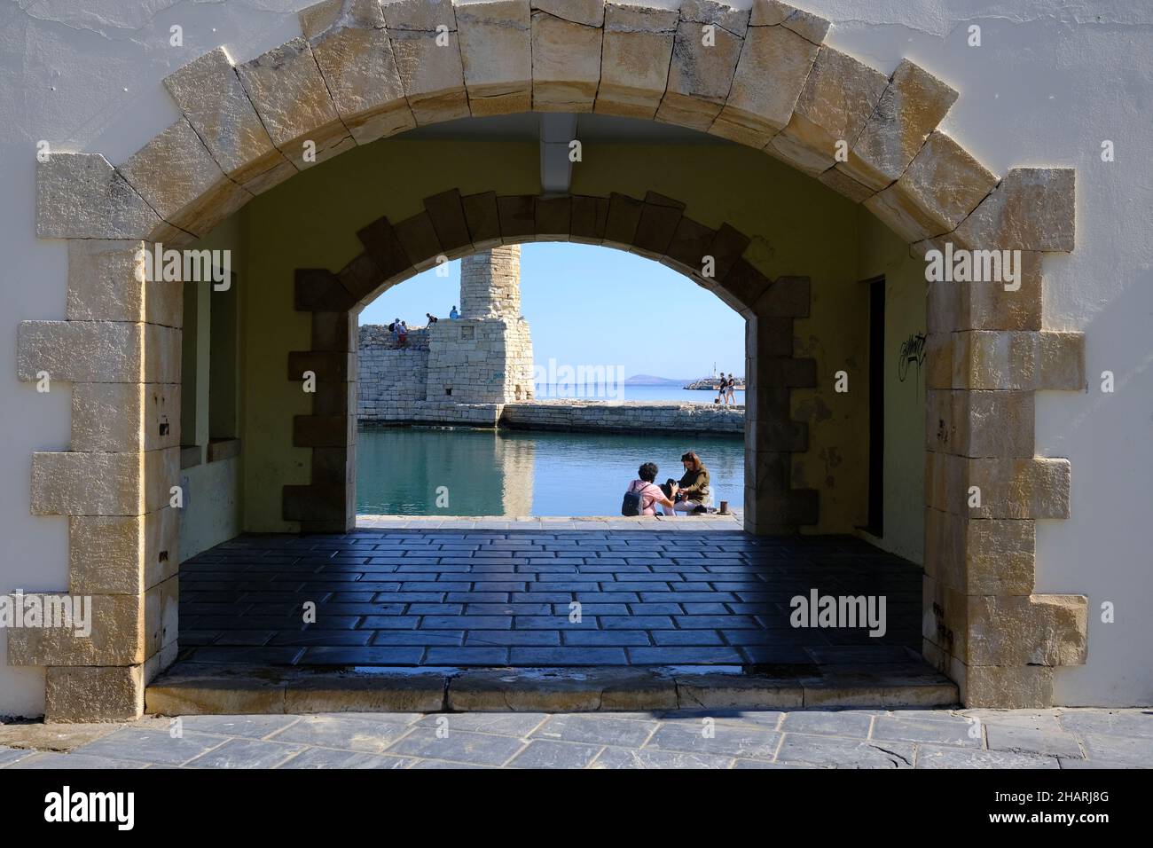 Vista di coppia e faro attraverso un portale nel muro di mare a Rethymno, Creta, Grecia Foto Stock