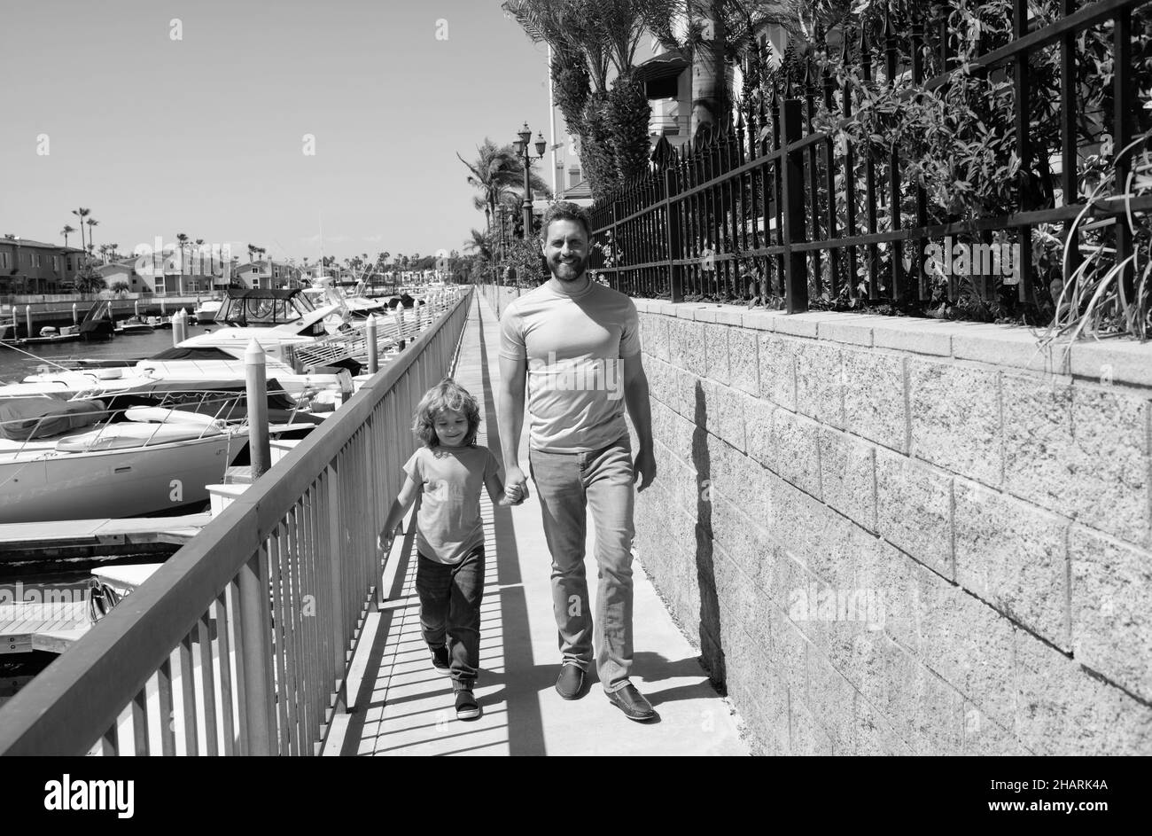 Camminare insieme. Padre e figlio Promenade tenendo le mani. L'uomo e il bambino si godono una piacevole passeggiata Foto Stock