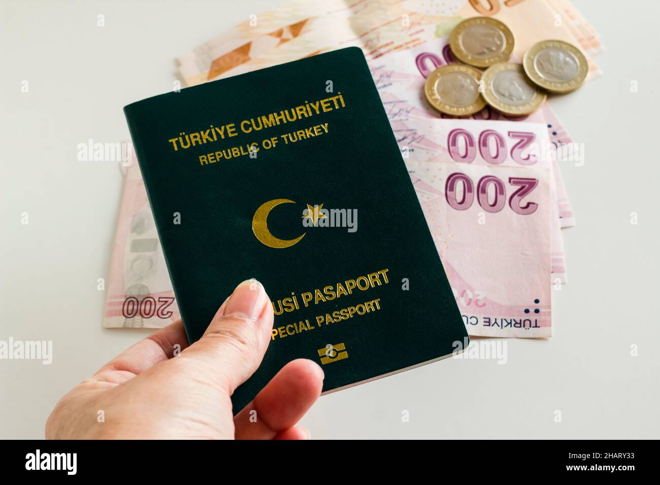 Passaporto ufficiale turco, verde di colore in mano su sfondo sfocato denaro, primo piano preso Foto Stock