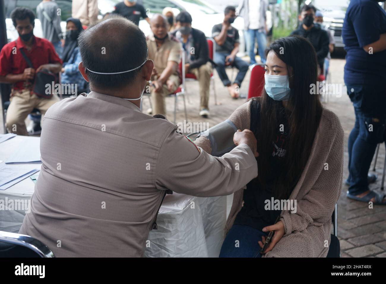 Makassar, Sulawesi meridionale, Indonesia. 13th Dic 2021. Un'attività gratuita di vaccinazione del Covid-19 svolta dalla direzione del traffico della polizia regionale del Sulawesi del Sud per i contribuenti dei veicoli presso l'ufficio Makassar Samsat. I contribuenti di veicoli che si dedicano alla vaccinazione ricevono un regalo dal funzionario di polizia che effettua la vaccinazione. Questa attività di vaccinazione COVID-19 viene effettuata in modo massiccio per raggiungere l'obiettivo che il 70% degli indonesiani sono stati vaccinati. (Credit Image: © Herwin Bahar/Pacific Press via ZUMA Press Wire) Foto Stock