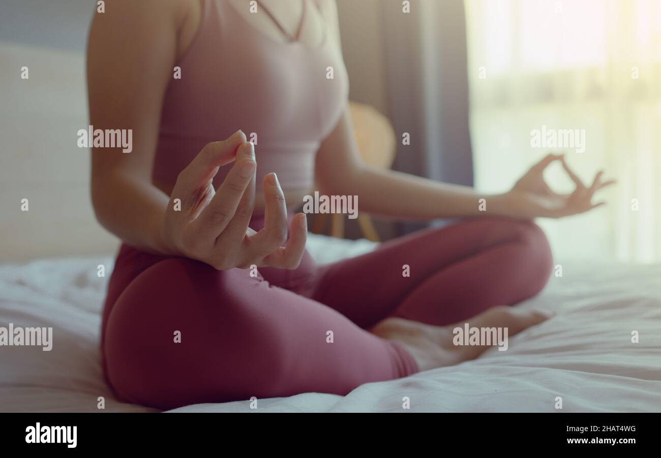 Primo piano mano di donna in pratica sportiva yoga lotus posa alla meditazione a casa, Wellness donna che fa yoga per la respirazione e la meditazione conforttabl Foto Stock