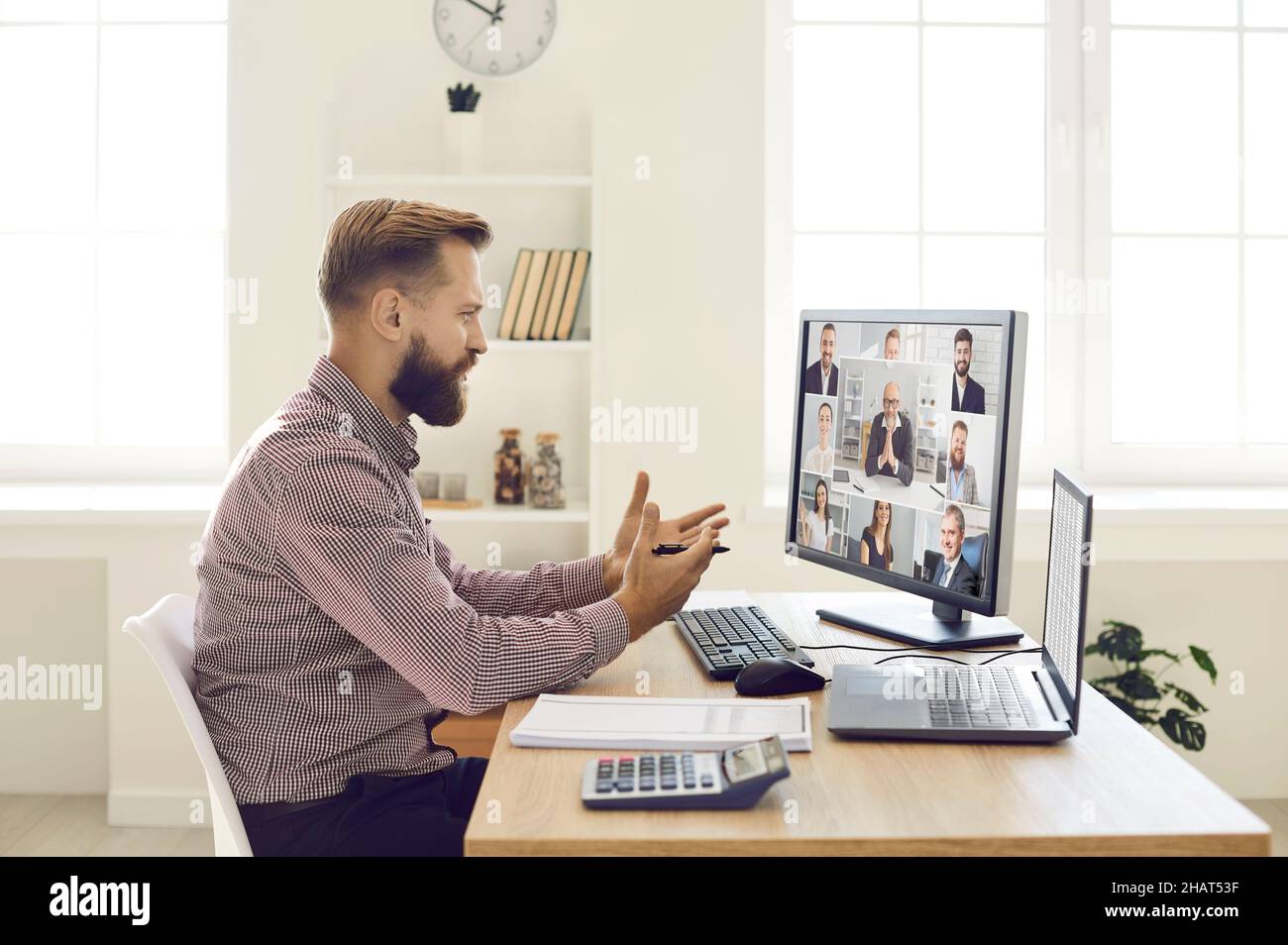 Uomo che parla con un team di persone durante una riunione aziendale remota sul suo computer Foto Stock