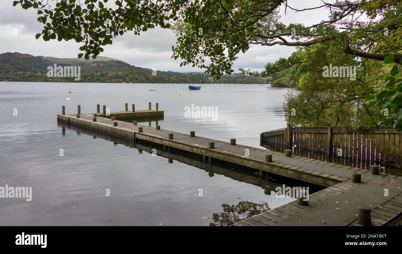 Un molo sul lago Ullswater nel distretto dei laghi inglesi. Ci sono alcune piccole imbarcazioni d'acqua ormeggiate in lontananza Foto Stock