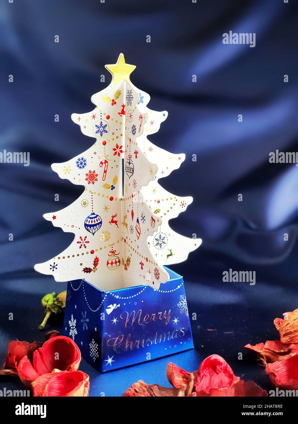 3D stand di carta bianca dell'albero di natale con sfondo satinato blu Foto Stock