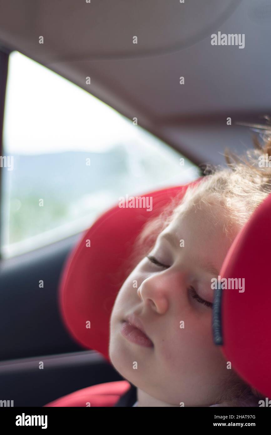 Incapace di sostenere il lungo viaggio, la bambina si addormentò nel suo comodo seggiolino per bambini. Messa a fuoco selettiva. Foto Stock