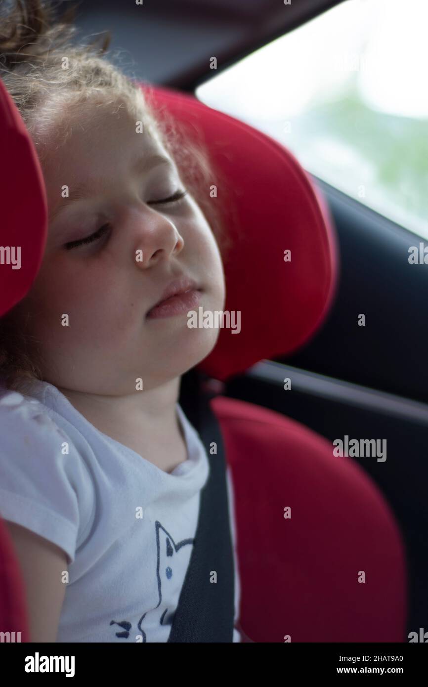 Incapace di sostenere il lungo viaggio, la bambina si addormentò nel suo comodo seggiolino per bambini. Messa a fuoco selettiva. Foto Stock