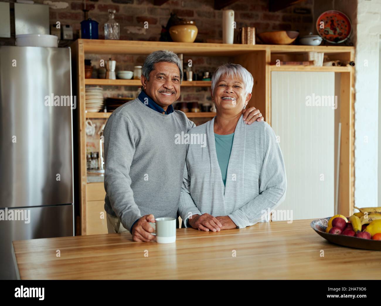 Ritratto di anziano coppia biraciale ridendo e guardando felicemente la macchina fotografica. Stile di vita sano e felice a casa. Foto Stock