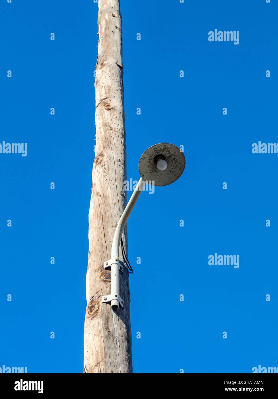 Semaforo. Streetlight retrò, lampadina appesa su palo elettrico in legno. Montante vintage con lampada. Sfondo cielo blu chiaro Foto Stock