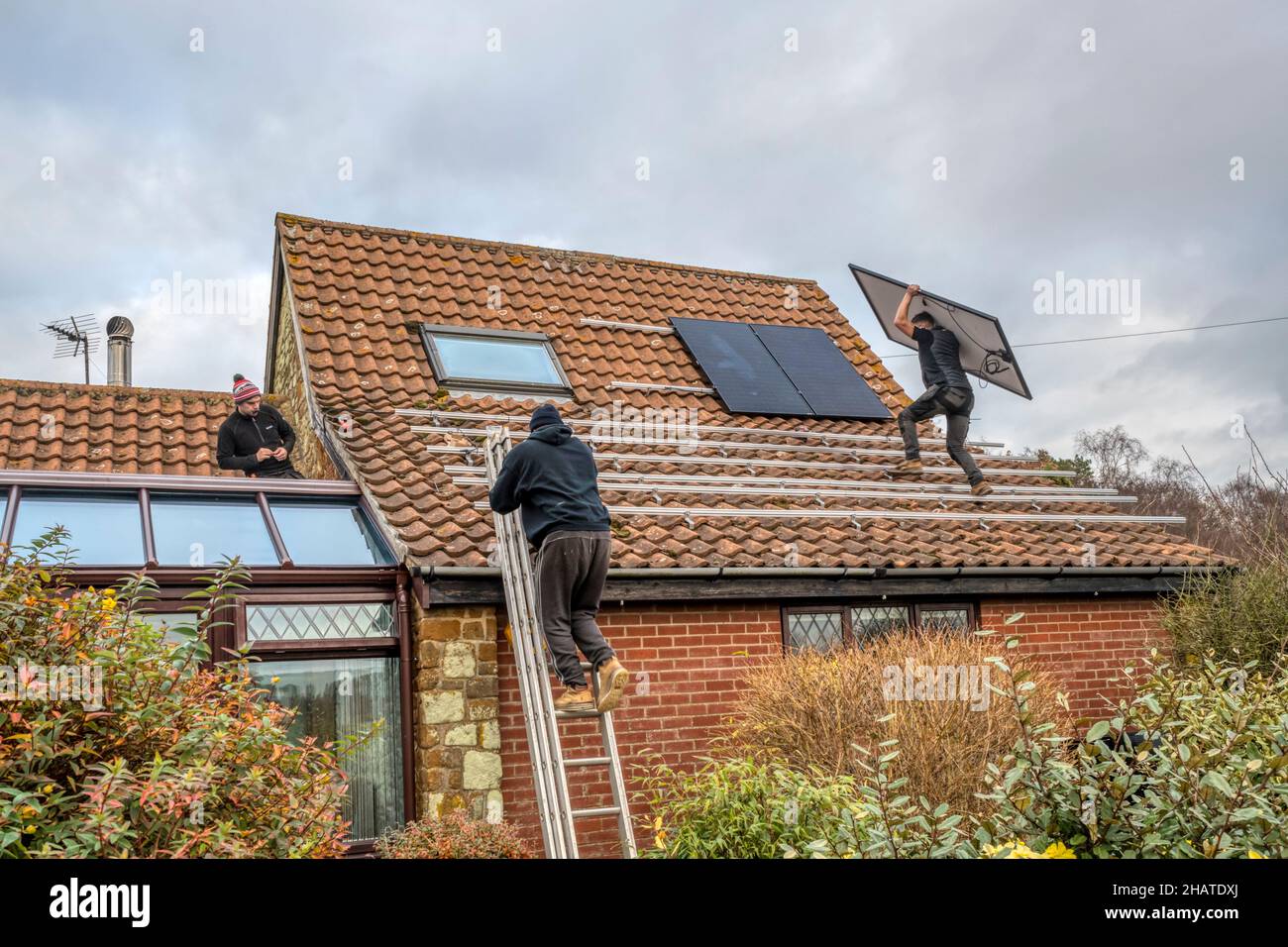 Lavoratori che installano pannelli solari o celle pv sul tetto a pannelli di un cottage Norfolk. NB: I locali nella fotografia sono proprietà liberate. Foto Stock