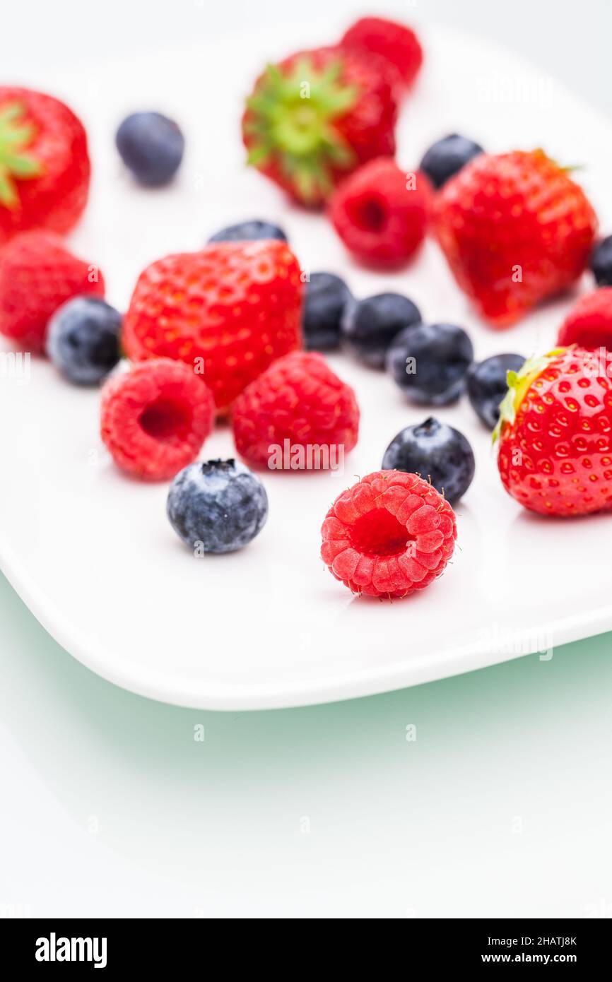 colorato, bacche, frutti di bosco, colorato, sfondo, molti, frutta, fragola, piatto, lampone, mirtillo, bianco, rosso, blu, ombra, riflessione, whi Foto Stock