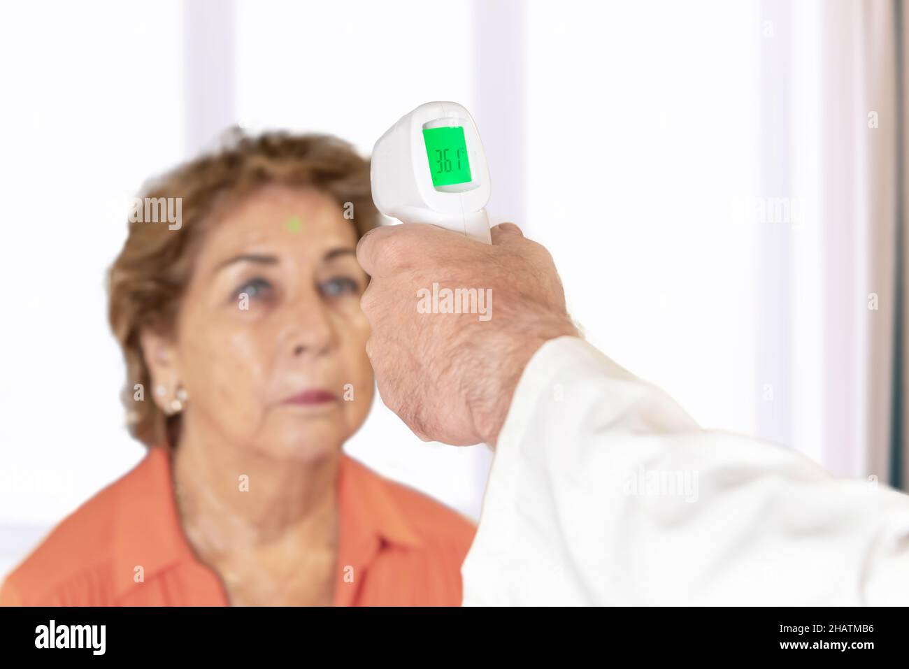 Il medico controlla la temperatura del paziente sulla fronte con un  termometro a pistola. Prevenzione del virus covid19 e omicron Foto stock -  Alamy