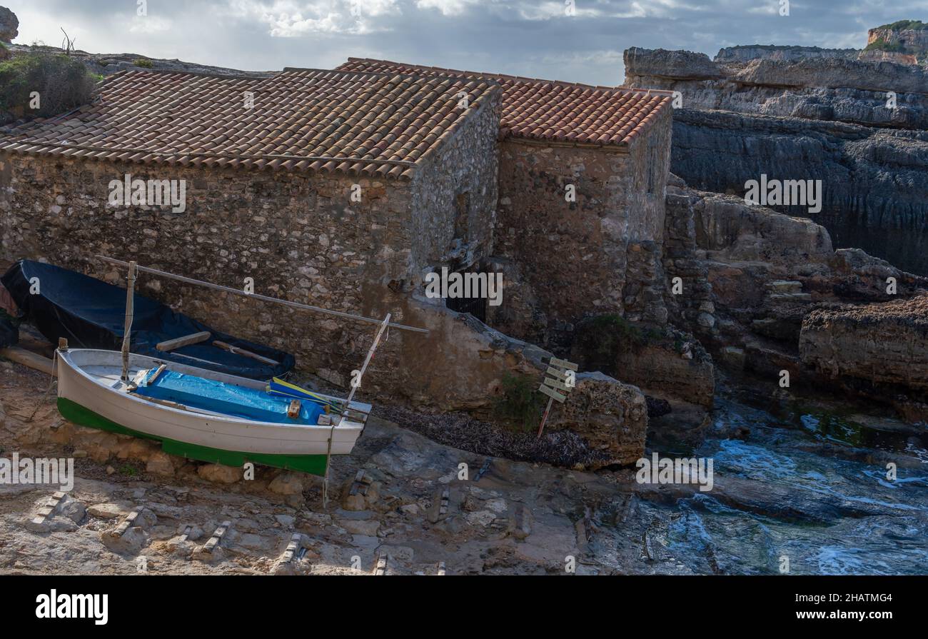 Paesaggio della costa rocciosa dell'isola di Maiorca, con un villaggio di pescatori costiero, una giornata invernale nuvolosa e soleggiata. Baia di S'Almonia Foto Stock