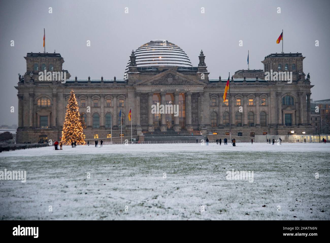 Berlino, Germania. 09th Dic 2021. Il Bundestag tedesco, Reichstag alla luce della sera, la neve è in campo, illuminato, un Weihaftertsbaum si erge di fronte ad esso, viste a Berlino, Germania il 9th dicembre 2021 Credit: dpa/Alamy Live News Foto Stock