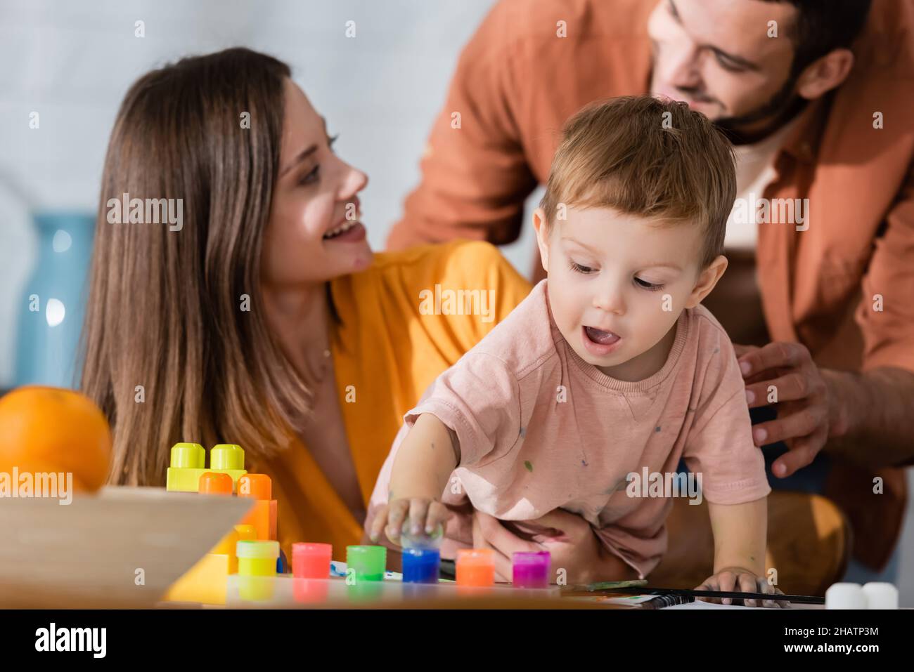 Bambino del toddler che gioca con la vernice vicino ai genitori nel paese Foto Stock